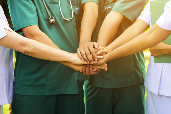 A group of nurses with their hands together in a show of teamwork 