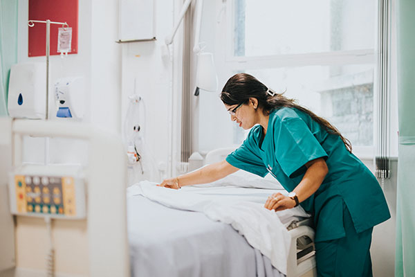 A nurse making the bed in a hospital room