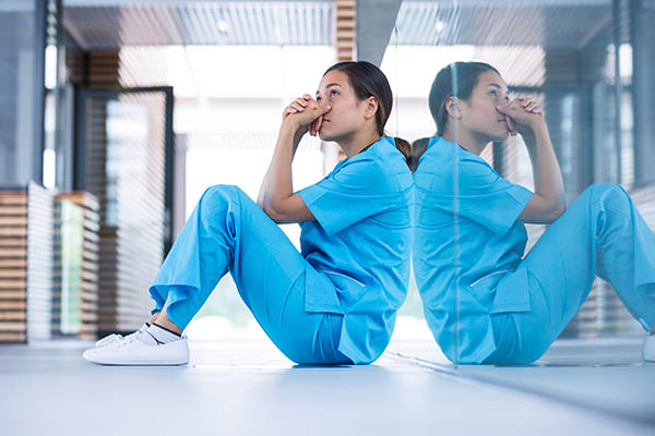 A nurse sitting on the floor looking off into the distance