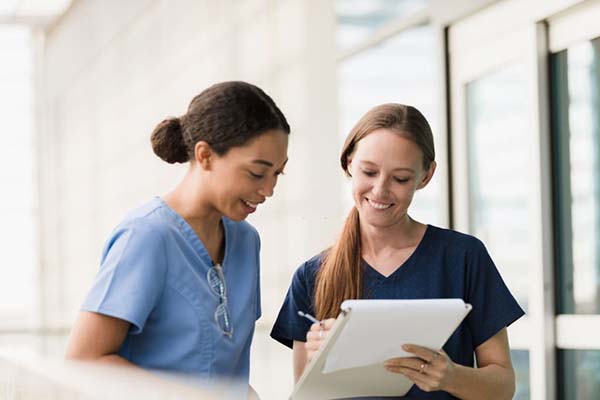 Two nurses looking at a clipboard together