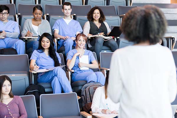Several nursing students in class with a nurse educator at the front of the room