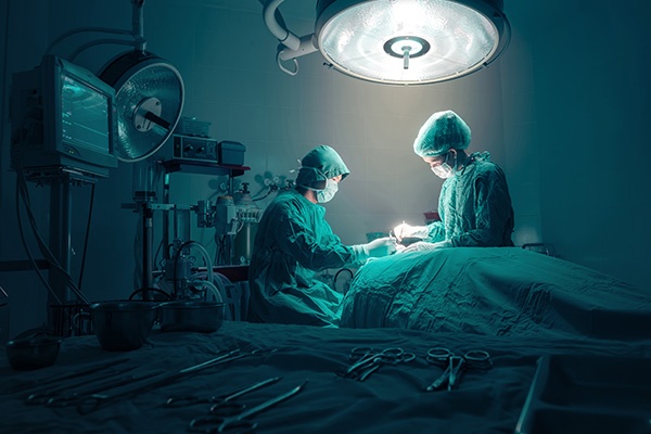 A surgeon and a nurse standing over a patient while in surgery