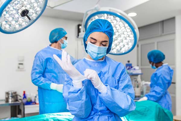 A nurse anesthetist putting on sterile gloves in an operating room