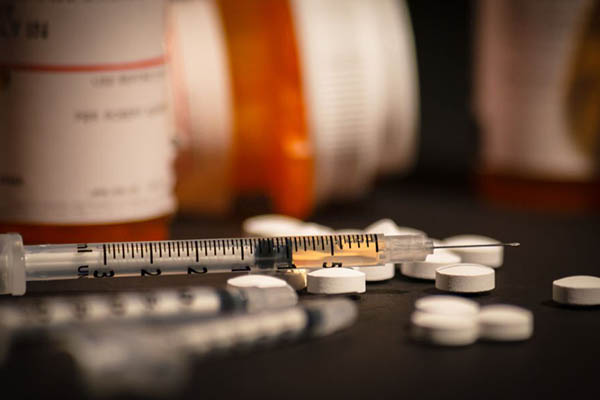 medications on a table including pills and a syringe filled with liquid
