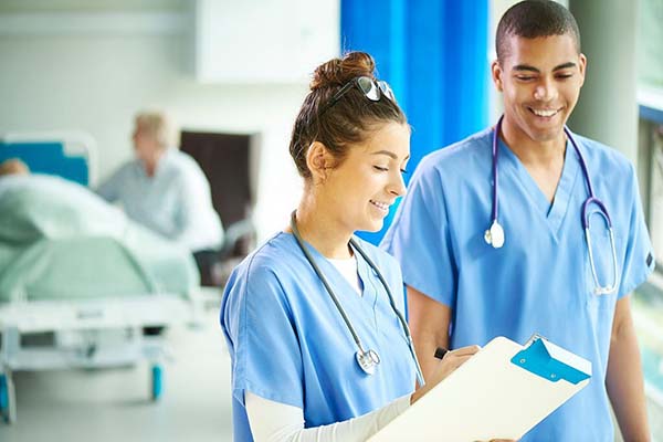 Two nurses looking at a clipboard and smiling