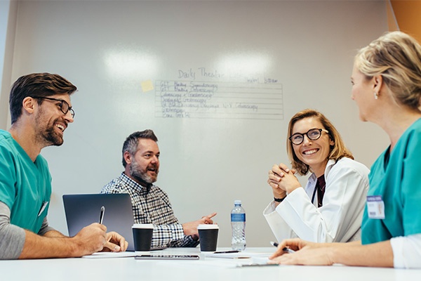 Healthcare professionals sitting together at a conference table smiling