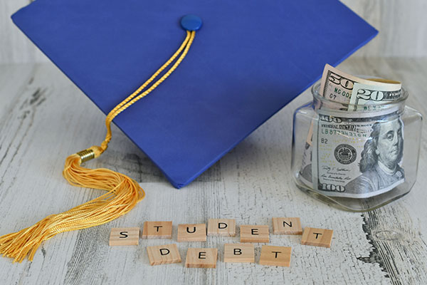 A graduation cap, money in a jar and the words Student Debt spelled out in letter tiles