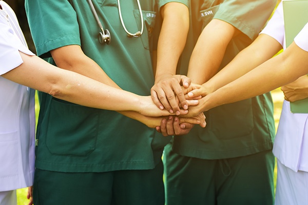 A group of healthcare workers putting their hands together for a high-five