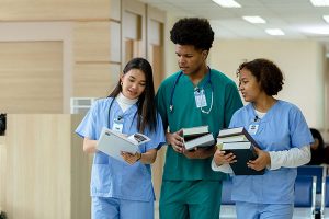 Three student nurses reviewing books and papers together