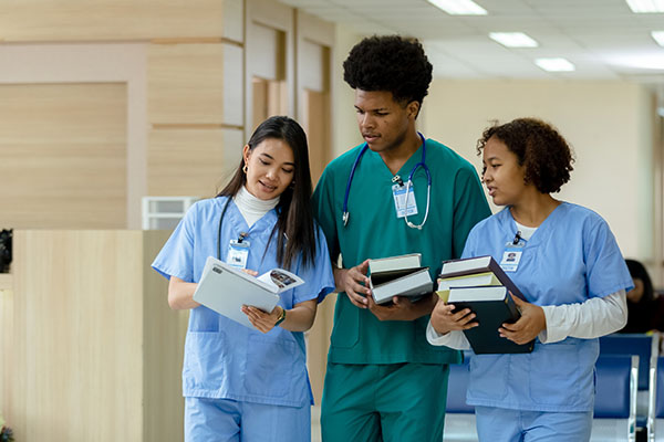 Three nursing students carrying books in nursing school