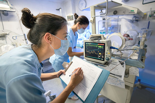 A nurse anesthetist looking at machines in a hospital room