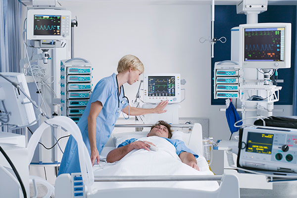 A nurse leaning over a patient sleeping in a hospital bed 