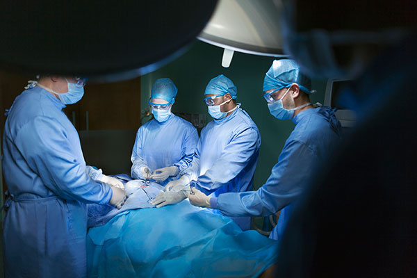 Nurse anesthetist with a doctor and nurses around a patient on an operating table