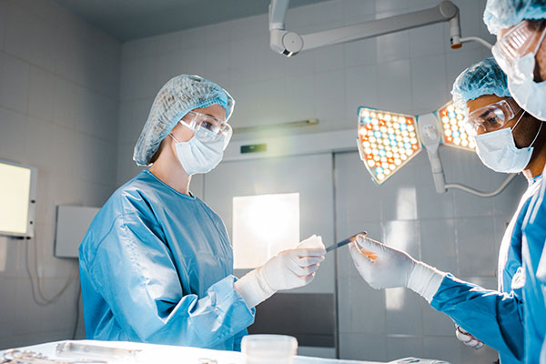 A nurse handing a scalpel to a doctor in an operating room