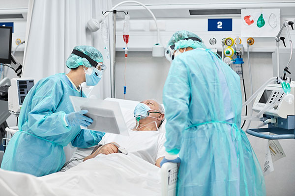 A nurse anesthetist and another nurse speaking with a patient in a hospital bed