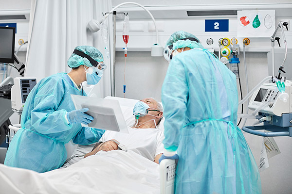 A nurse and a CRNA speaking with an older patient in a hospital room