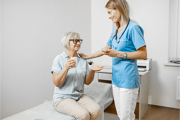 A nurse giving an older patient medications