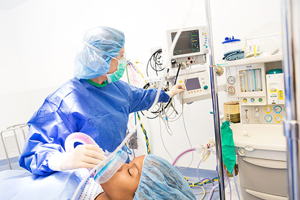 A CRNA giving a patient anesthetic gas in an operating room
