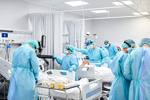 Several healthcare workers in a hospital room with multiple patients