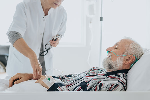 A nurse checking the pulse of an older patient in a hospital bed