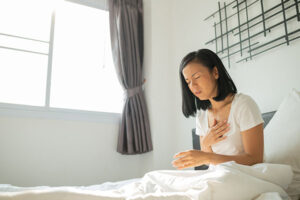 A woman sitting up in a bed coughing