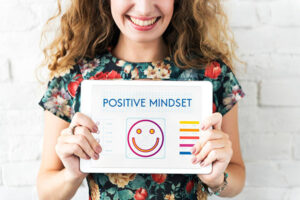 A woman holding a sign that says "Positive Mindset" on it