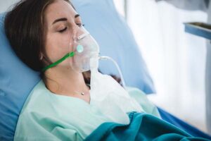 A woman laying in a hospital bed with an oxygen mask on
