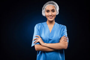 A female nurse wearing scrubs and looking at the camera smiling
