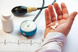 A person holding medications in their hand with a blood pressure cuff nearby