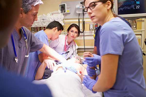 A group of ICU  nurses and doctors surrounding a patient in the ICU