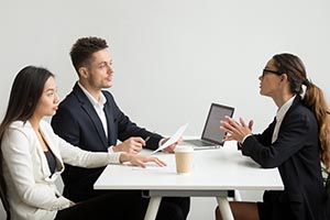 Two people interviewing another person who is sitting across the desk from them