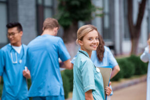 A group of nursing students walking and one of them is turned looking back towards the camera