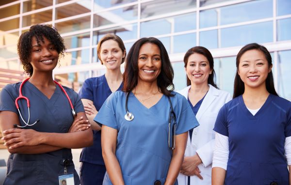 A diverse group of women nurses and nurse anesthetists smiling at the camera