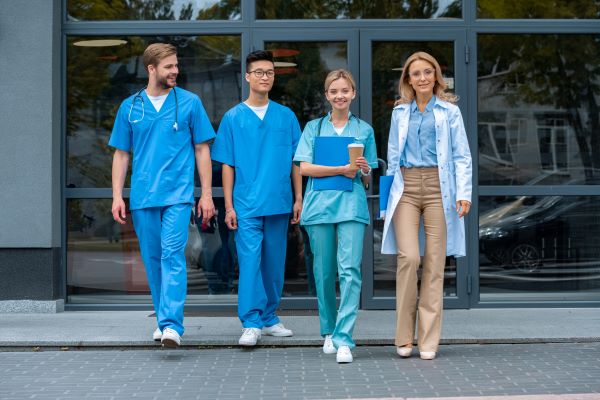 Nurses and nursing students walking out of a hospital towards the camera and smiling