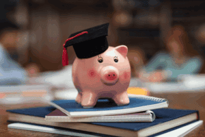 a piggy bank on a pile of notebooks from graduate school